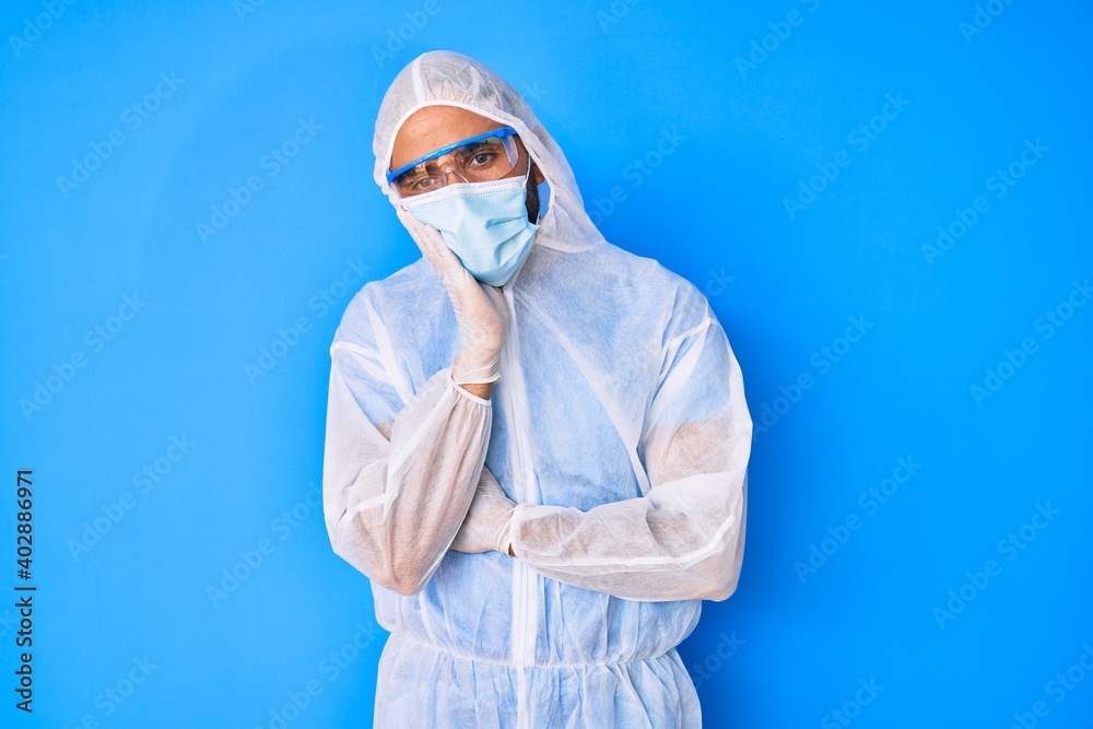 Young hispanic man wearing doctor coronavirus protection uniform thinking looking tired and bored with depression problems with crossed arms.