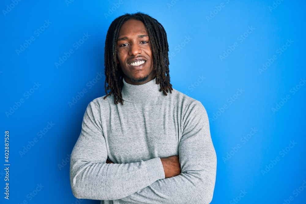 African american man with braids wearing turtleneck sweater happy face smiling with crossed arms looking at the camera. positive person. African american man with braids wearing turtleneck sweater happy face smiling with crossed arms looking at the camera. positive person.