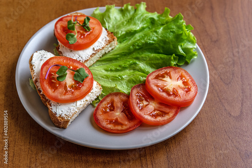 dried diet bread with curd cheese, tomatoes and lettuce on a ceramic plate