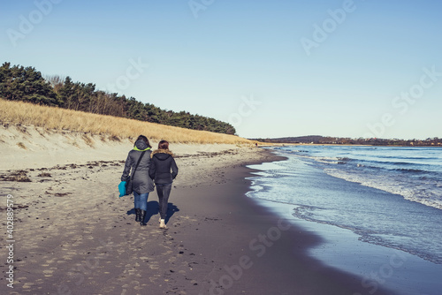 Mutter und Tochter spazieren am Strand photo