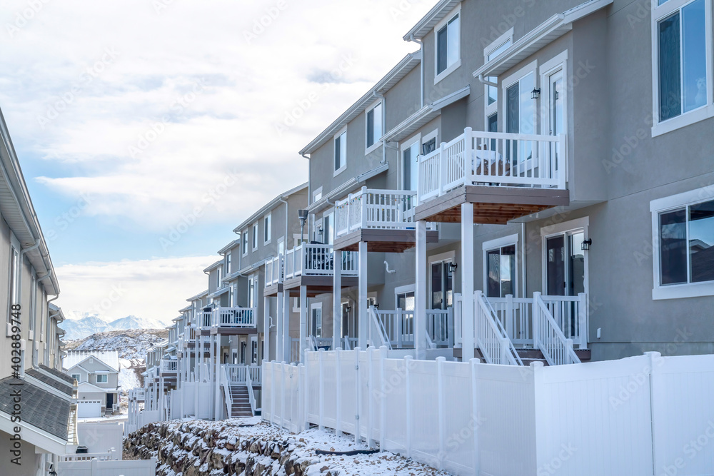 Townhouses on a snowy suburban neighborhood against cloudy blue sky in winter