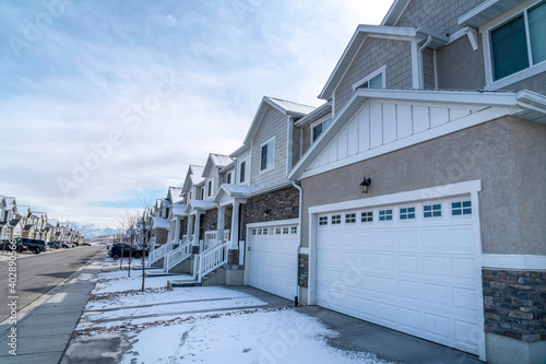 Suburban neighborhood with road along snowy driveways of townhouses in winter