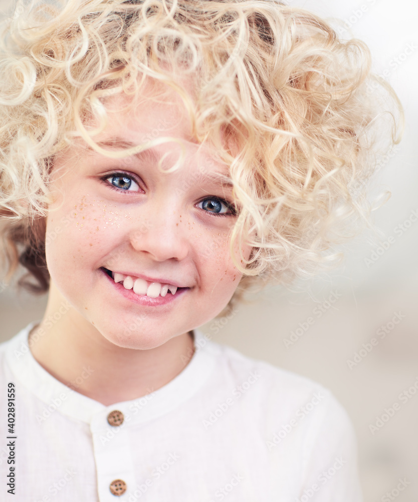 portrait of beautiful happy blonde boy with curly hair