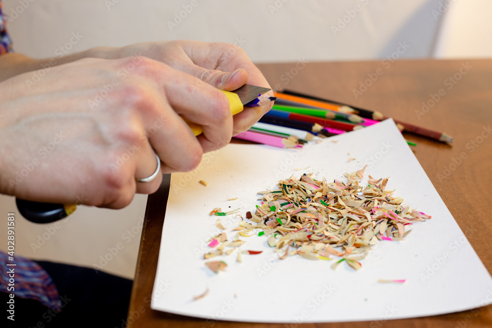 A man sharpens a pencil with a stationery knife A man sharpens a pencil with a stationery knife