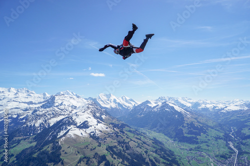 Man glides in tracking suit above mountains