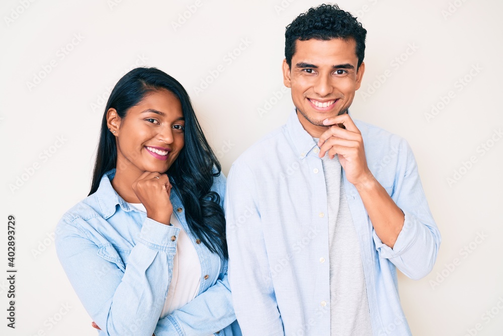 Beautiful latin young couple wearing casual clothes looking confident at the camera with smile with crossed arms and hand raised on chin. thinking positive. Beautiful latin young couple wearing casual clothes looking confident at the camera with smile with crossed arms and hand raised on chin. thinking positive.