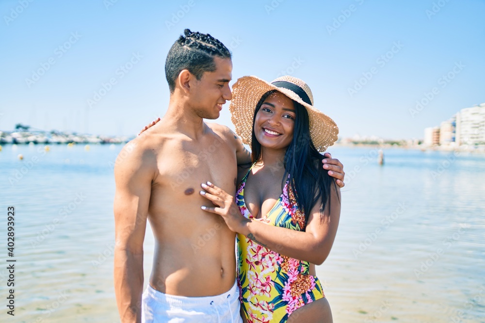 Young latin couple wearing swimwear smiling happy and hugging at the beach. Young latin couple wearing swimwear smiling happy and hugging at the beach.