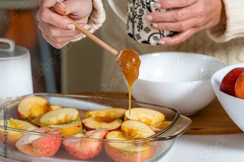 female hands with stick pouring apples with honey in a glass container and prepare them for cooking