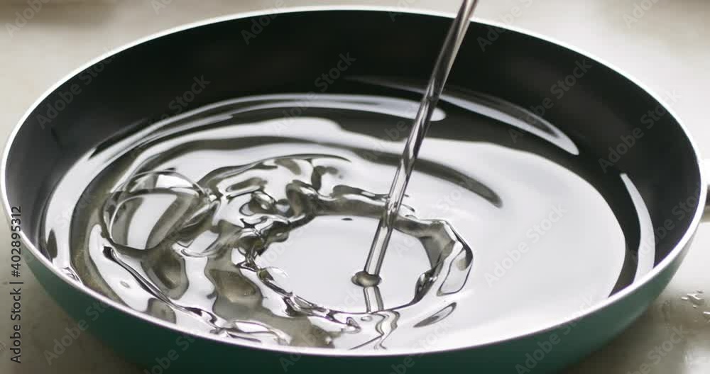 Close-up of pouring oil into a frying pan for cooking. Cook pours oil into a frying pan. Slow motion Close-up of pouring oil into a frying pan for cooking. Cook pours oil into a frying pan. Slow motion