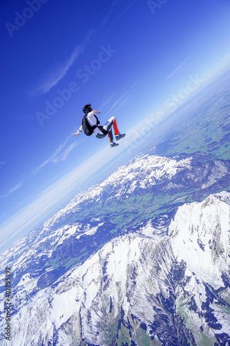 Skydiver performs stunts above snowcapped mountains
