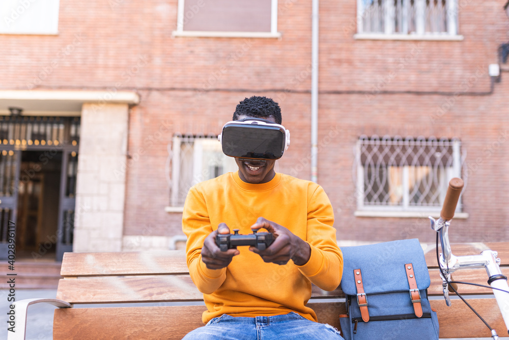 African American Young Man Playing Video Games on Virtual Reality Glasses Outdoors. African American Young Man Playing Video Games on Virtual Reality Glasses Outdoors.