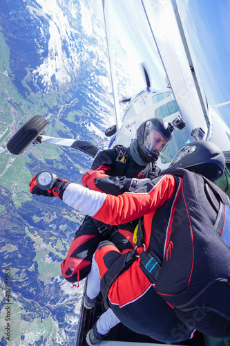 Skydivers jump out of airplane above snowcapped mountains