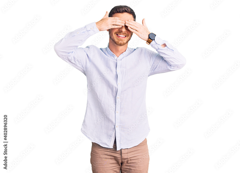 Fototapeta premium Handsome young man with bear wearing elegant business shirt and glasses covering eyes with hands smiling cheerful and funny. blind concept.