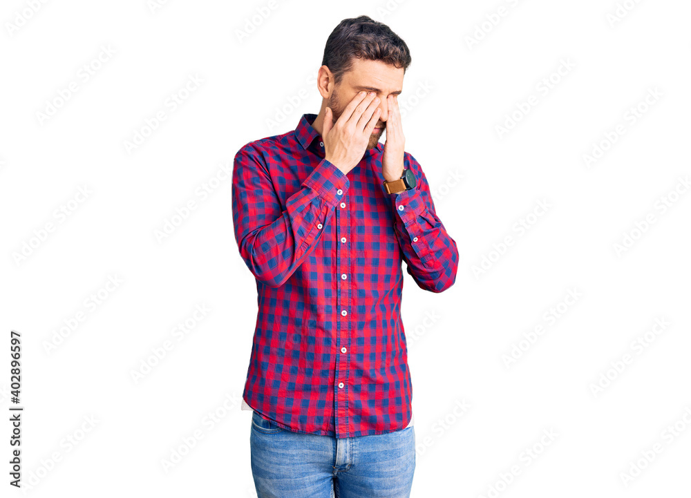Handsome young man with bear wearing casual shirt rubbing eyes for fatigue and headache, sleepy and tired expression. vision problem Handsome young man with bear wearing casual shirt rubbing eyes for fatigue and headache, sleepy and tired expression. vision problem