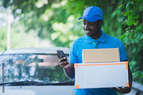 African postal delivery courier man using smart phone and delivering package