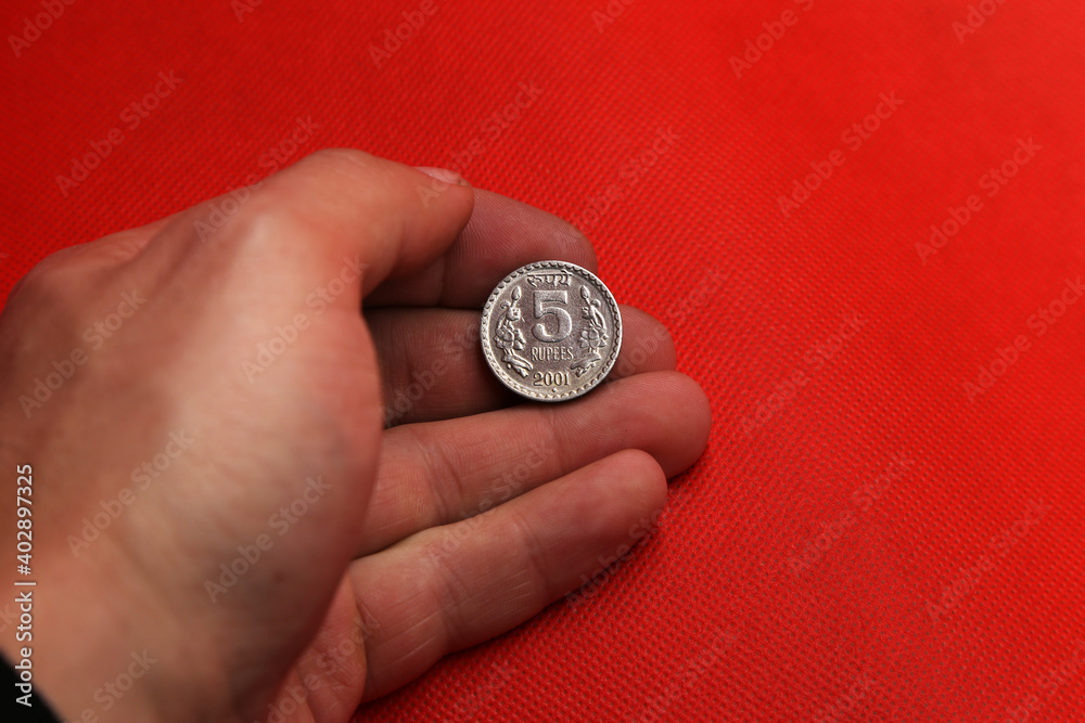 Old coin from India in hand on red background Old coin from India in hand on red background