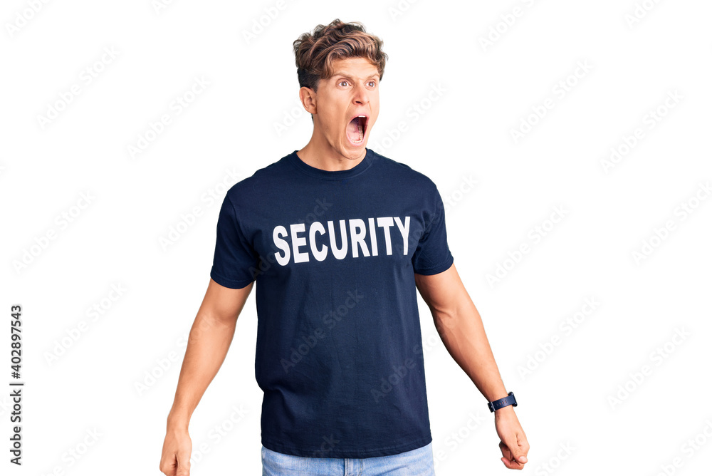 Young handsome man wearing security t shirt angry and mad screaming frustrated and furious, shouting with anger. rage and aggressive concept.