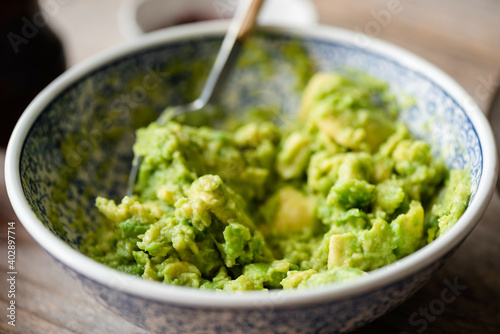 Mashed avocado, guacamole sauce in a bowl, closeup view. Healthy vegan food