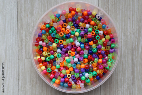 Multicolored plastic beads for handicraft are scattered on the table