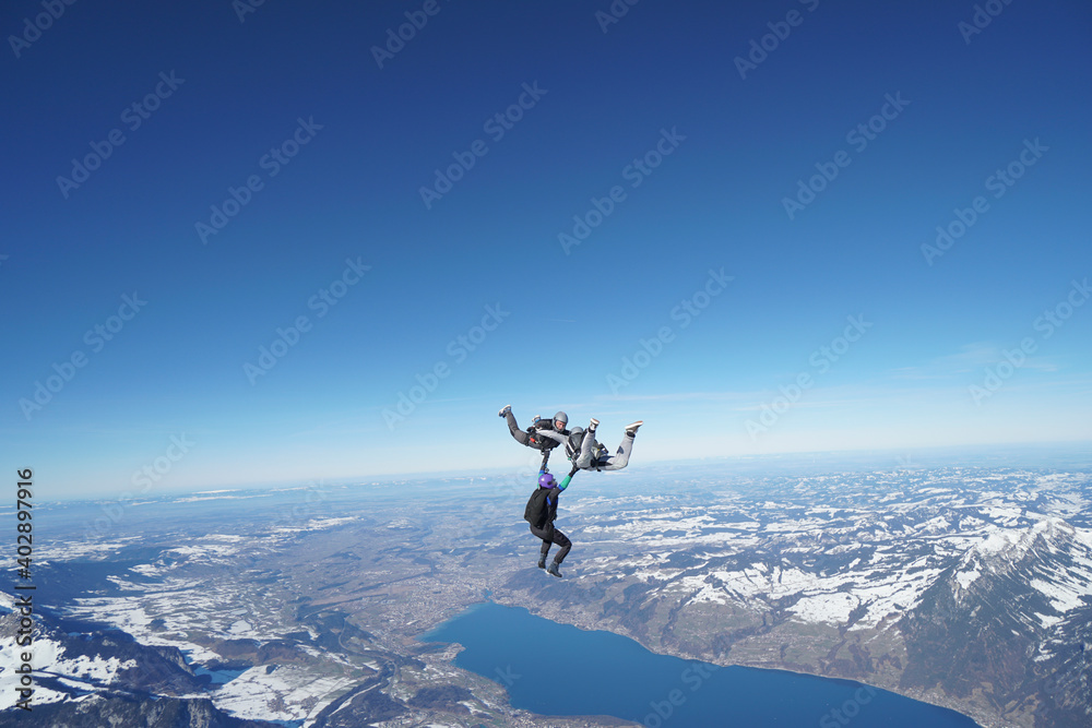 Skydivers perform stunts above snowcapped mountains