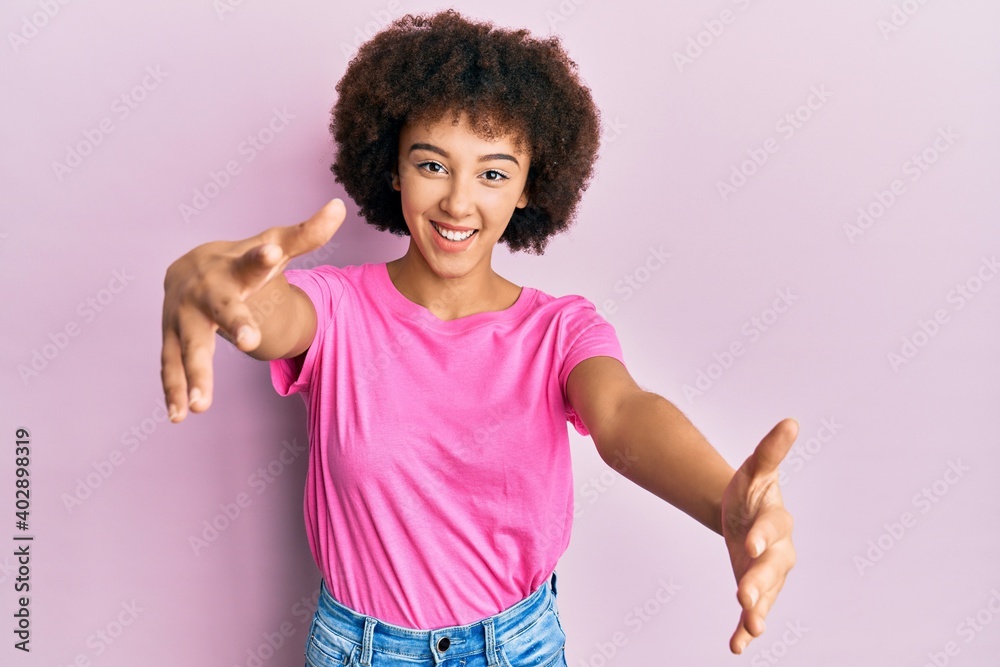 Young hispanic girl wearing casual clothes looking at the camera smiling with open arms for hug. cheerful expression embracing happiness. Young hispanic girl wearing casual clothes looking at the camera smiling with open arms for hug. cheerful expression embracing happiness.