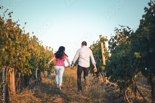Young, romantic couple running through the vineyard