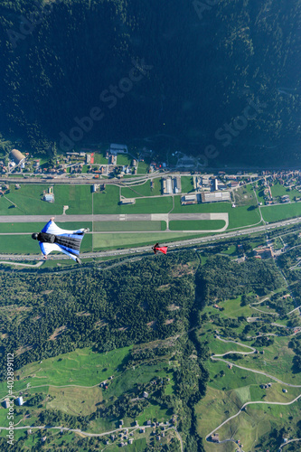 Wingsuit fliers glide in formation above airport landing strip photo