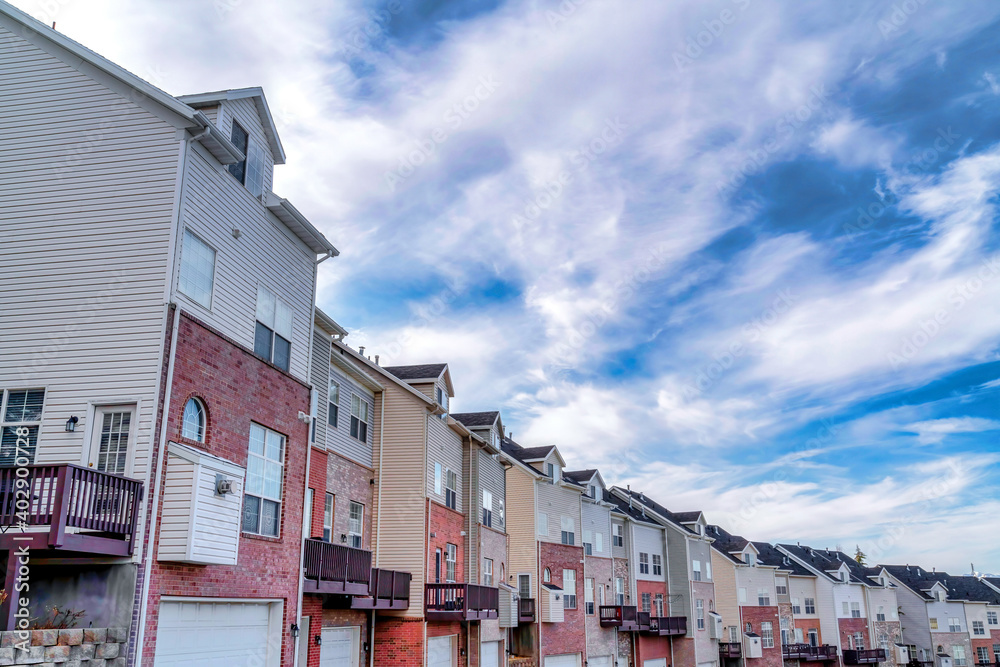 Row of three storey townhouses in the valley under vibrant blue sky with clouds