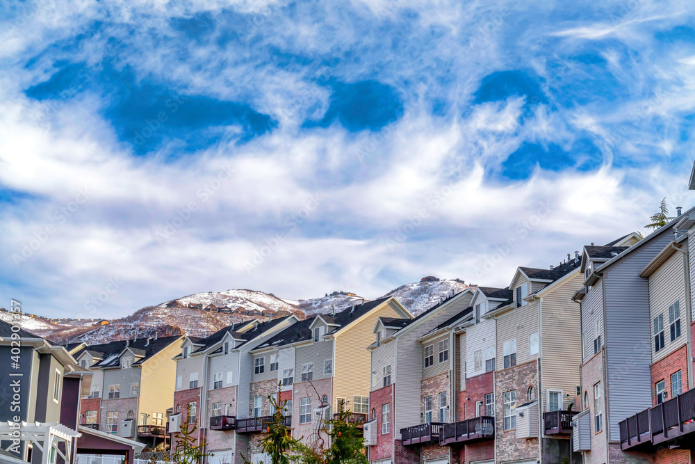 Snowy peak of Wasatch Mountains behind row of multi storey homes in the valley