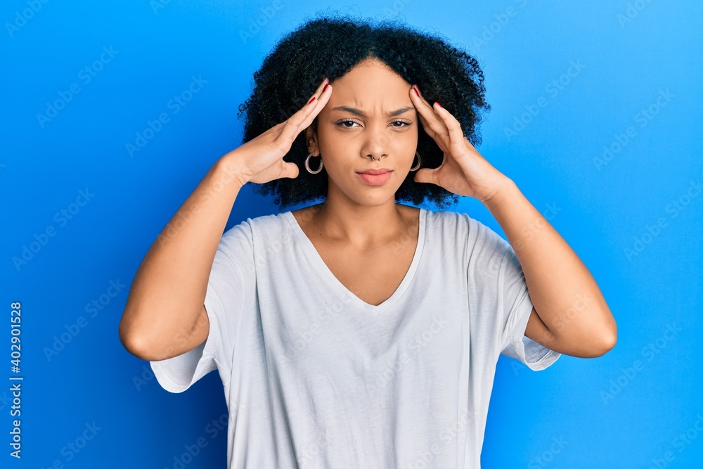 Young african american girl wearing casual white t shirt with hand on head, headache because stress. suffering migraine. Young african american girl wearing casual white t shirt with hand on head, headache because stress. suffering migraine.