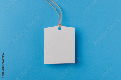 empty white rectangular paper tag on a rope on blue background