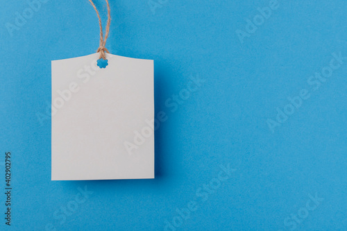 empty white rectangular paper tag on a rope on blue background