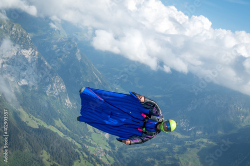 Wingsuit flier glides over mountains at sunrise