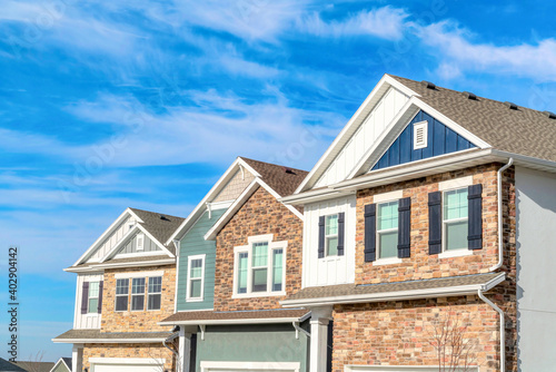 Фотография Exterior view of homes with gable roofs stone brick and wooden siding walls