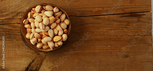 Pistachio nuts in a container made of natural material on a wooden surface selective focus.