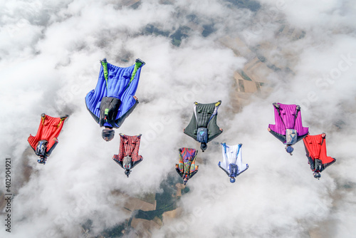 Team of wingsuit fliers glide in formation at sunset photo