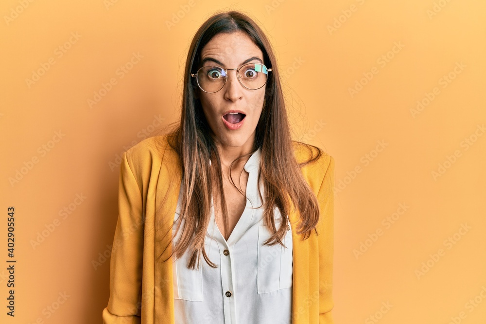 Young beautiful woman wearing business style and glasses afraid and shocked with surprise and amazed expression, fear and excited face.