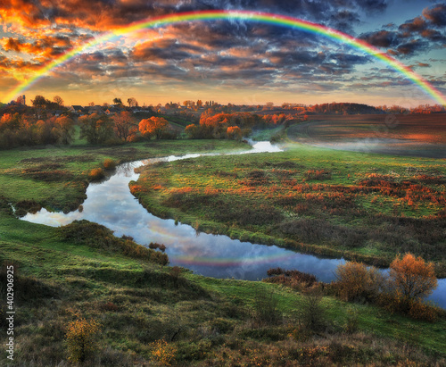 Amazing rainbow over the small rural river. autumn morning 