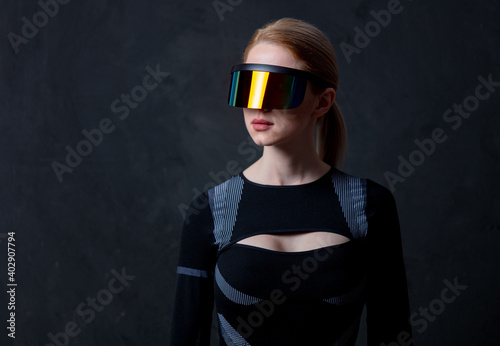 Blonde android female in VR glasses and suit on dark background. photo