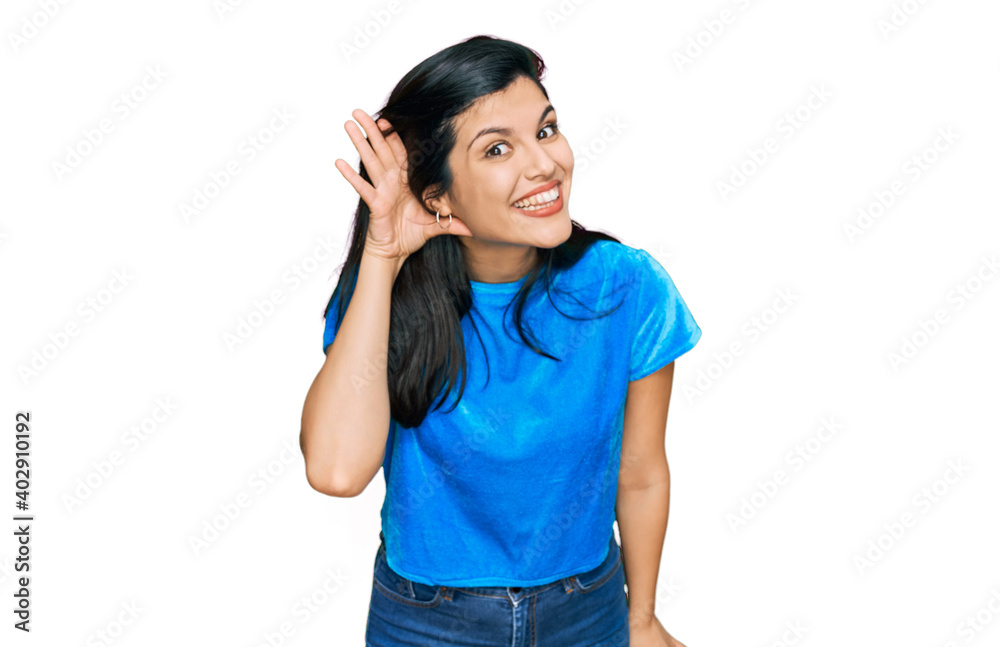 Young hispanic woman wearing casual clothes smiling with hand over ear listening an hearing to rumor or gossip. deafness concept. Young hispanic woman wearing casual clothes smiling with hand over ear listening an hearing to rumor or gossip. deafness concept.