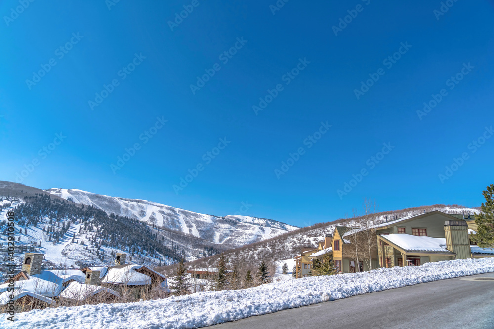 Houses on snow covered hill in winter with mountain road in the foreground