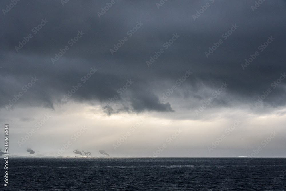 Stormy gray skies above the Southern Ocean with a sunbeam hitting the water, as a nature background 

