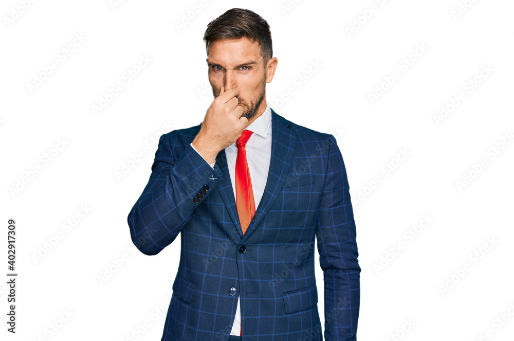 Handsome man with beard wearing business suit and tie smelling something stinky and disgusting, intolerable smell, holding breath with fingers on nose. bad smell Handsome man with beard wearing business suit and tie smelling something stinky and disgusting, intolerable smell, holding breath with fingers on nose. bad smell