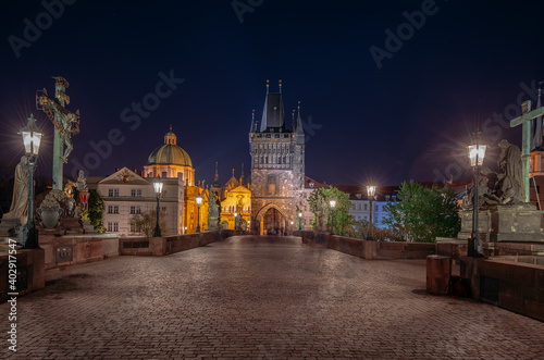 Empty Charles Bridge in the center of Prague during first wave of Covid-19 pandemy in the night with blue sky and yellow lights  Czechia  Europe