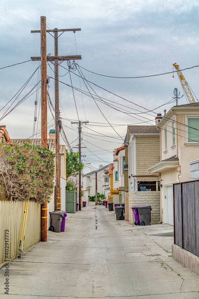 Narrow road along houses in Long Beach California neighborhood with cloudy sky