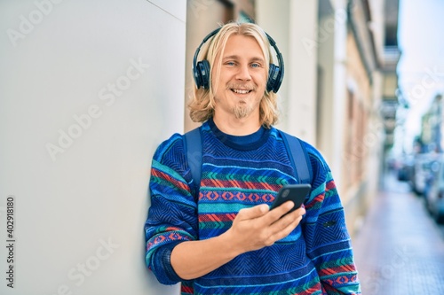 Εκτύπωση καμβά Young scandinavian student man smiling happy using smartphone and headphones at the city