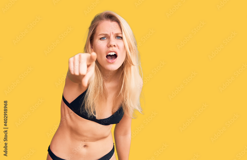 Fototapeta premium Young beautiful blonde woman wearing bikini pointing displeased and frustrated to the camera, angry and furious with you