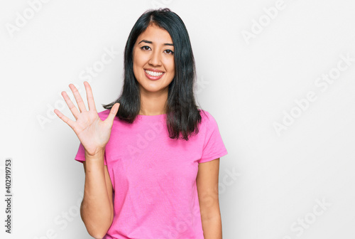 Beautiful asian young woman wearing casual pink t shirt showing and pointing up with fingers number five while smiling confident and happy.