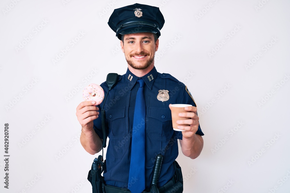Young caucasian man wearing police uniform holding take away coffee and donut smiling with a happy and cool smile on face. showing teeth. Young caucasian man wearing police uniform holding take away coffee and donut smiling with a happy and cool smile on face. showing teeth.
