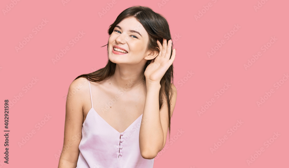 Fototapeta premium Young beautiful caucasian girl wearing casual clothes smiling with hand over ear listening an hearing to rumor or gossip. deafness concept.